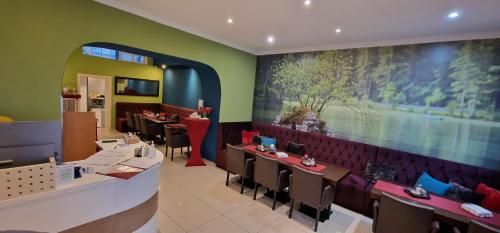 Hotel Cara Vita Cologne في كولونيا: مطعم بطاولات وكراسي و لوحة كبيرة على الحائط