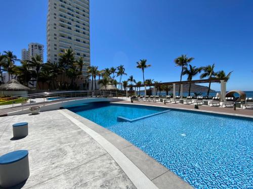 a large swimming pool with chairs and the ocean at Camino al Mar 802 Vista al Mar in Mazatlán