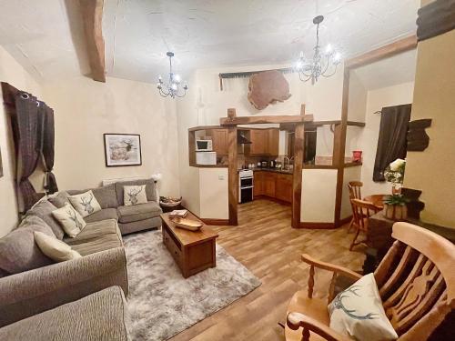 a living room with a couch and a kitchen at RURAL stone barn with Log Burner, tranquil setting in Usk