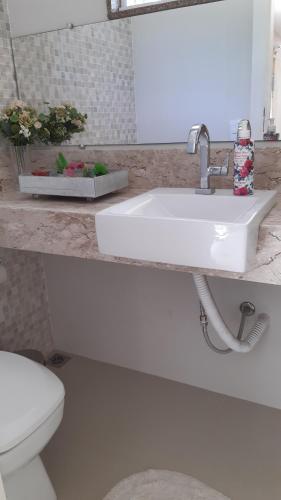 uma casa de banho com um lavatório branco e um WC. em Casa Aconchegante em Saquarema