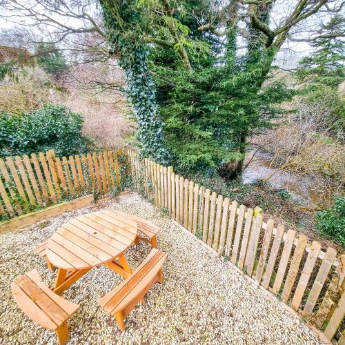 a wooden picnic table and two benches next to a fence at Burnside Cottage in Sleights