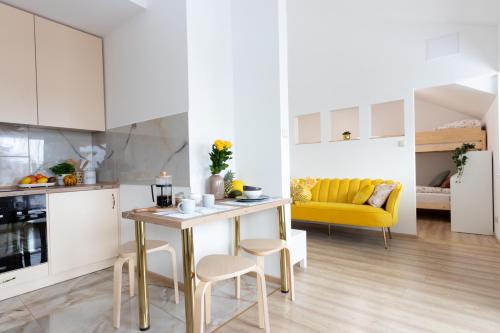 a kitchen and living room with a table and yellow couch at Apartament Gorki Male in Tuszyn
