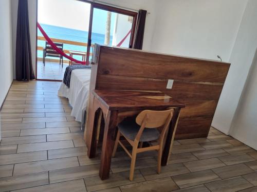 einen Schreibtisch mit einem Stuhl neben einem Bett und einem Fenster in der Unterkunft Posada Ziga Playa in Mazunte