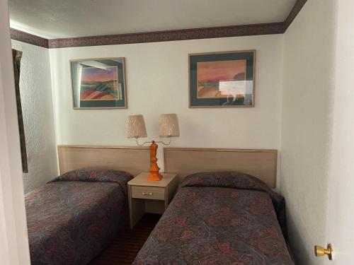 a bedroom with two beds and two pictures on the wall at Sands Motel in El Paso