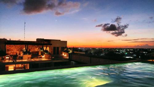 a swimming pool on top of a building with a sunset at Syrena Luxury Caribbean in Playa del Carmen
