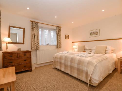 a bedroom with a bed and a dresser and a window at Valley Farm Cottage in Woodbridge