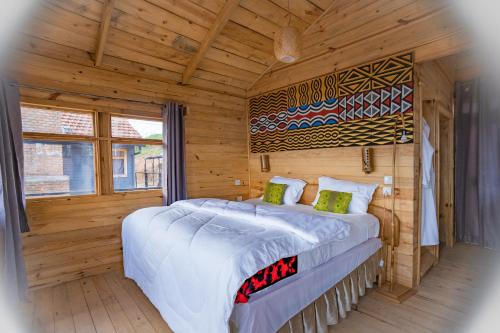 una camera da letto con un grande letto in una camera in legno di Nyungwe Nziza Ecolodge a Kitabi