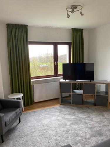 a living room with a flat screen tv and green curtains at Ferienhof Kröger in Bielefeld