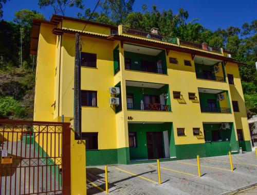 a yellow and green building with a balcony at Apartamento Mar Brasil II in Ubatuba