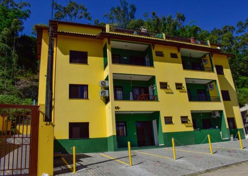 a yellow and green building with a balcony at Apartamento Mar Brasil II in Ubatuba