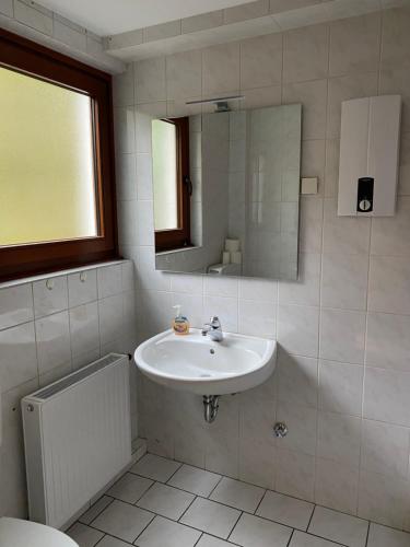 a white bathroom with a sink and a mirror at Ferienhof Kröger in Bielefeld