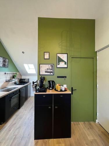 - une cuisine avec un mur vert et un comptoir dans l'établissement Le Central 3 - Pépite en centre ville d’Elbeuf, à Elbeuf