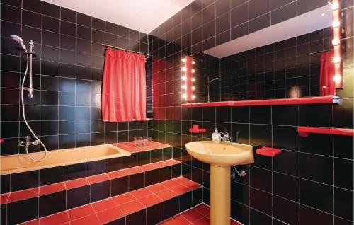 W wyłożonej czarnymi kafelkami łazience znajduje się umywalka i wanna. w obiekcie Stunning Home In Klimno With Outdoor Swimming Pool w mieście Klimno