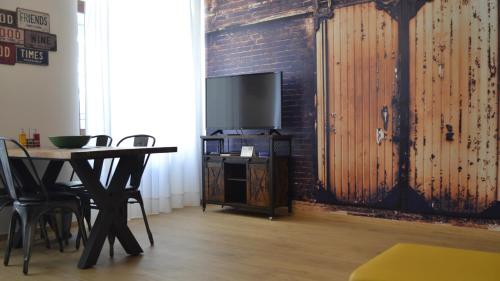 Habitación con mesa, TV y pared de ladrillo. en RivApartmentsDowntowN Urban en Riva del Garda