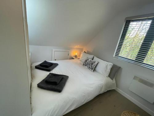 1 dormitorio con 1 cama blanca y 2 toallas en The Annexe - woodland views and close to beach! en Barton on Sea