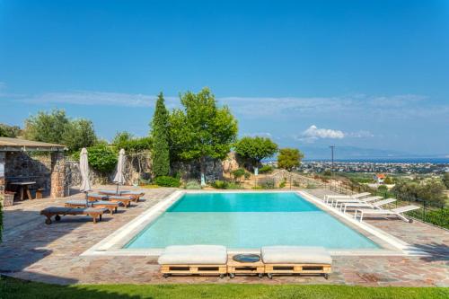 a swimming pool with chaise lounge chairs and a pool at Terra Casa Private Villa in Aegina Island in Vathí