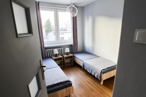 a small room with two beds and a window at Grójecka Apartament in Warsaw