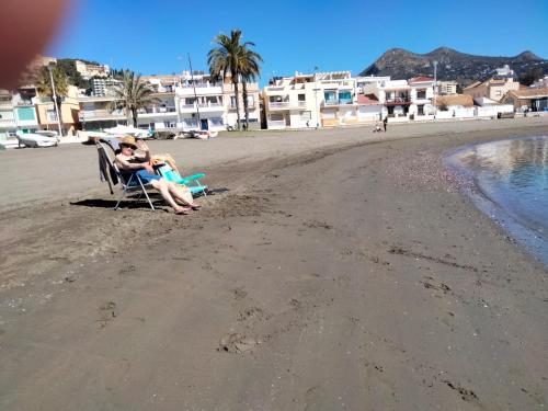 two people sitting in a chair on the beach at Casita La Playa in Málaga
