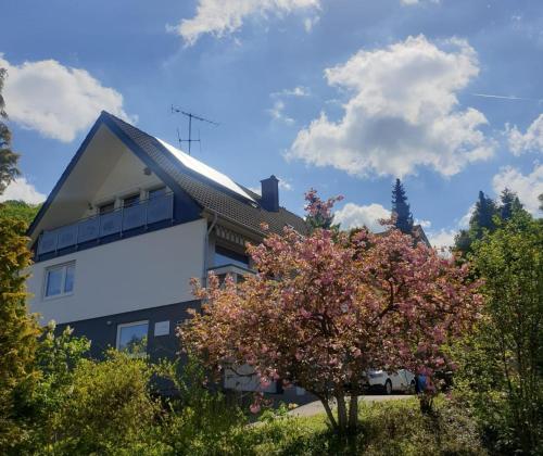 ein Gebäude mit einem blühenden Baum davor in der Unterkunft Ferienwohnung mit toller Aussicht in Albstadt