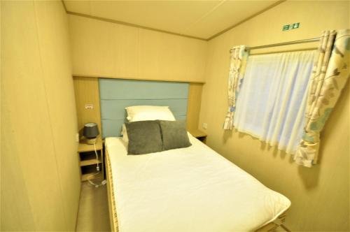 a small bed in a small room with a window at Caravan by Camber Sands 2 in Camber