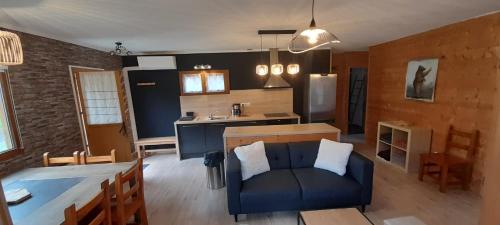 een woonkamer met een bank en een keuken bij Chalet de l'Ours Brun, gîte 3 étoiles in Gère-Belesten