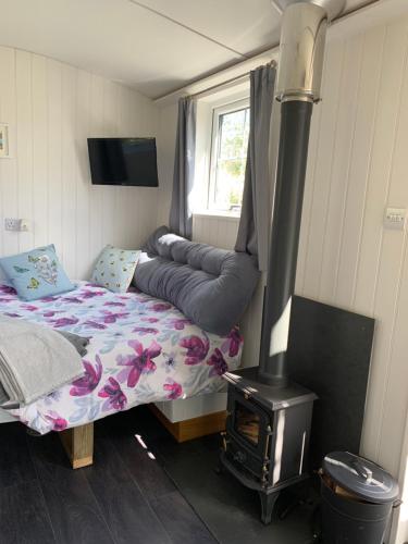 a bedroom with a bed and a stove at Tides Reach, Deluxe Shepherds hut, 100m from the Beach in Saint Merryn