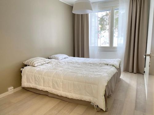 a bedroom with a large bed with a window at City Apartment Sotilaskatu in Iisalmi