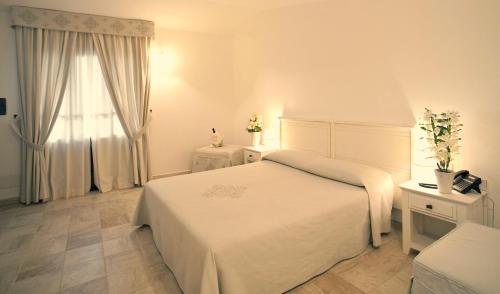 a white bedroom with a bed and a window at Albergo Diffuso Mannois in Orosei