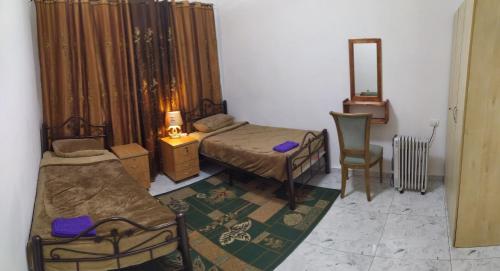 een slaapkamer met 2 bedden, een stoel en een spiegel bij حنضلة درويش in Bethlehem