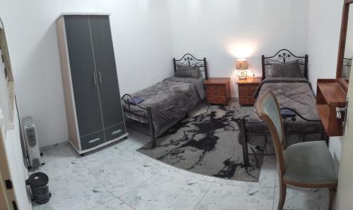 een slaapkamer met twee bedden, een bureau en een stoel bij حنضلة درويش in Bethlehem