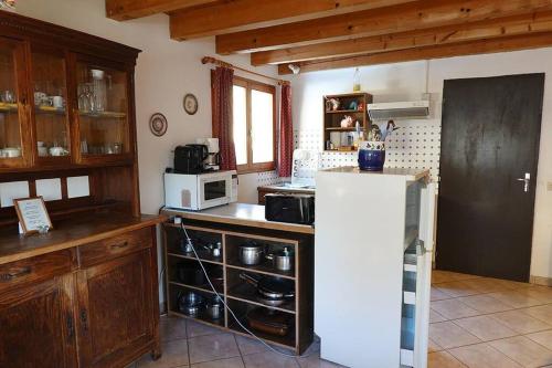 La cuisine est équipée d'un réfrigérateur blanc et d'un four micro-ondes. dans l'établissement Appartement dans vielle ferme au coeur des Vosges, à Plainfaing