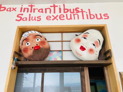 two masks in a window of a sushi restaurant at Yamagata Guesthouse山形ゲストハウス in Murayama
