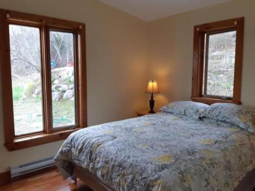 a bedroom with a bed and two windows at Oceanfront Garden Cottage - Gateway to Attractions and Towns, Private Cove Mooring in Chester