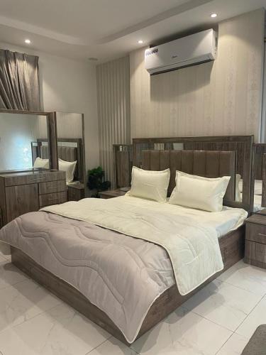 1 dormitorio con 1 cama grande con sábanas y almohadas blancas en منتجع قرية الريف الفندقية en Taif