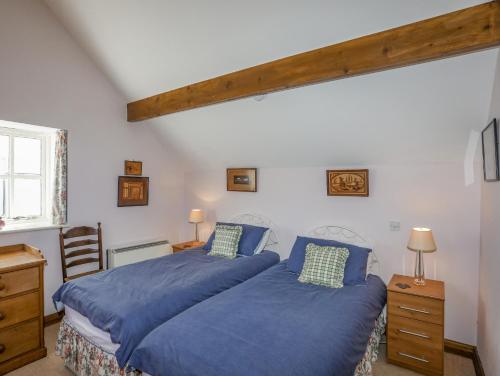 1 Schlafzimmer mit 2 Betten und blauer Bettwäsche in der Unterkunft Llo Bach in Abergele