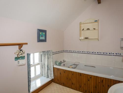 ein Bad mit einer Badewanne und einem Fenster in der Unterkunft Llo Bach in Abergele