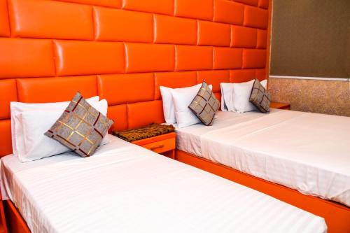 two beds in a room with orange walls at The Royal Sea Clifton in Karachi