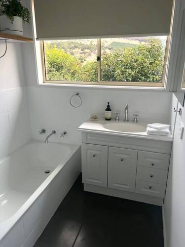 a bathroom with a tub and a sink and a window at Richmond Cottage in Richmond