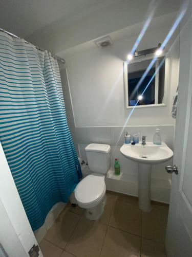 ein Badezimmer mit einem WC und einem Waschbecken mit einem blauen Duschvorhang in der Unterkunft Departamento dos dormitorios nuevo in Curicó