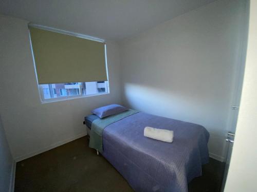 a small bedroom with a bed and a window at Departamento dos dormitorios nuevo in Curicó