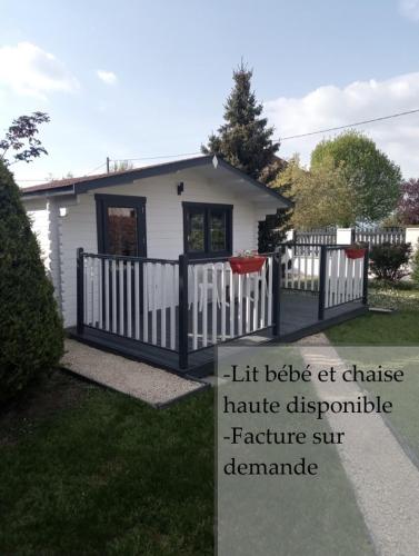 une petite maison blanche avec une clôture et un panneau dans l'établissement Chalet climatisé et chauffé a Faverges de la Tour, à Faverges-de-la-Tour