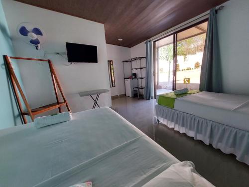 a room with two beds and a tv and a window at Hotel Casa Carlota Tamarindo in Tamarindo