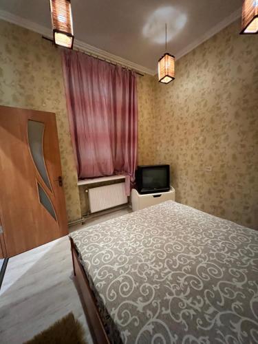 1 dormitorio con 1 cama grande y TV en 10 Kotliarska Moisha House, en Leópolis