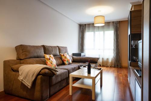 - un salon avec un canapé brun et une table dans l'établissement Como en casa, à Oviedo