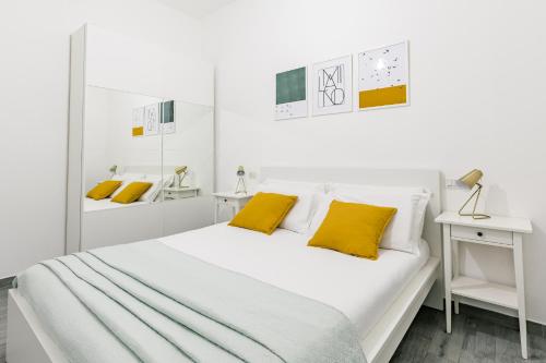 a white bedroom with a large bed with yellow pillows at Appartamento La Fortezza in Milan