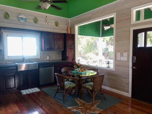 cocina con mesa, sillas y ventana en Serenity Beach Cottages, en Utila