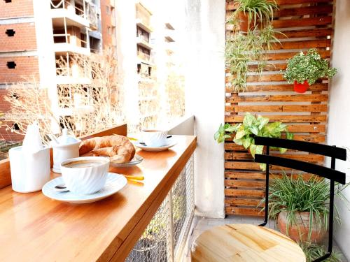 a table with cups of coffee and a croissant on a balcony at Franca Estadías Temporarias in Rosario
