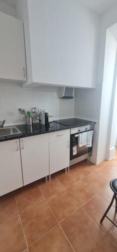 a kitchen with white cabinets and a black counter top at S.Soares Beato 6.2D in Lisbon