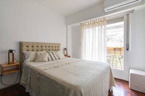 a white bedroom with a large bed and a window at Franca Estadías Temporarias in Rosario