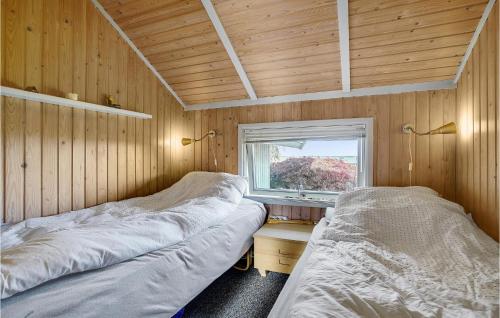 Awesome Home In Kge With House Sea View في Valløby: سريرين في غرفة خشبية مع نافذة